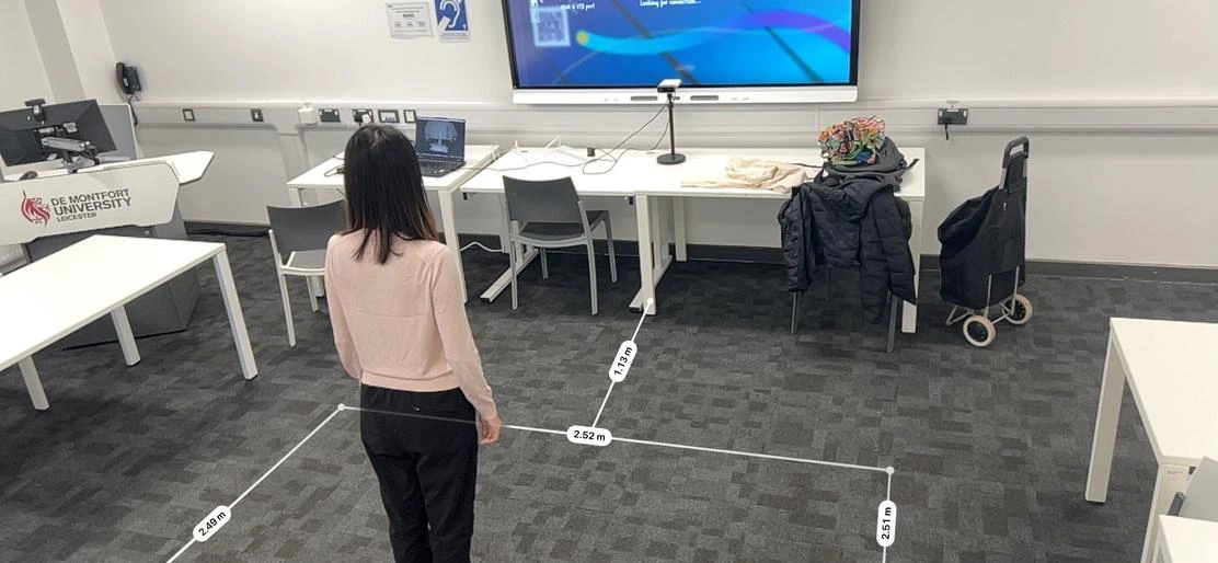 The internal pilot room, with floor dimensions overlaid around a person facing a shared display.